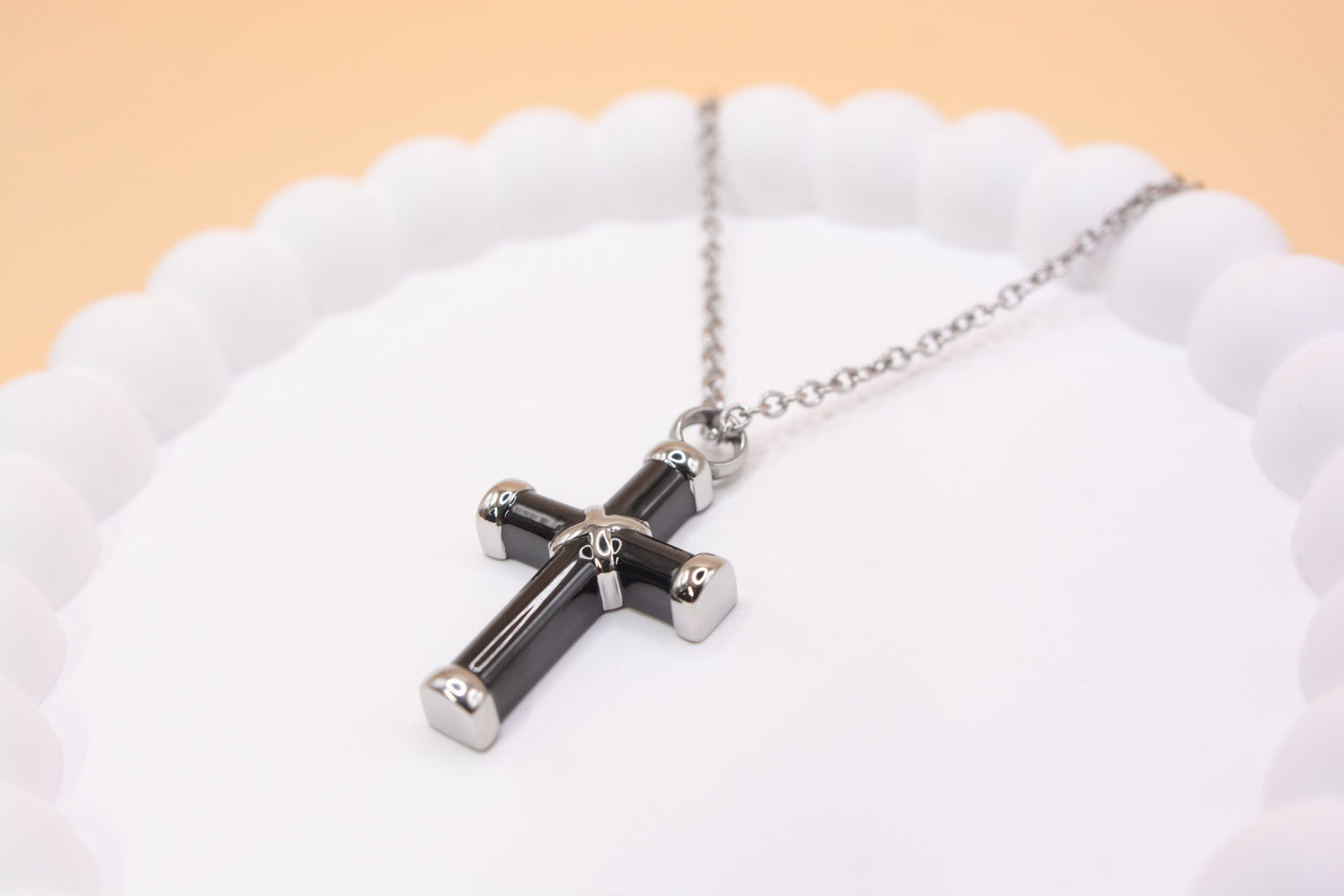 A black and silver coloured stainless steel cross pendant, ideal for any gender. It can be self-filled with cremation ashes or sand from a loved ones favourite beach