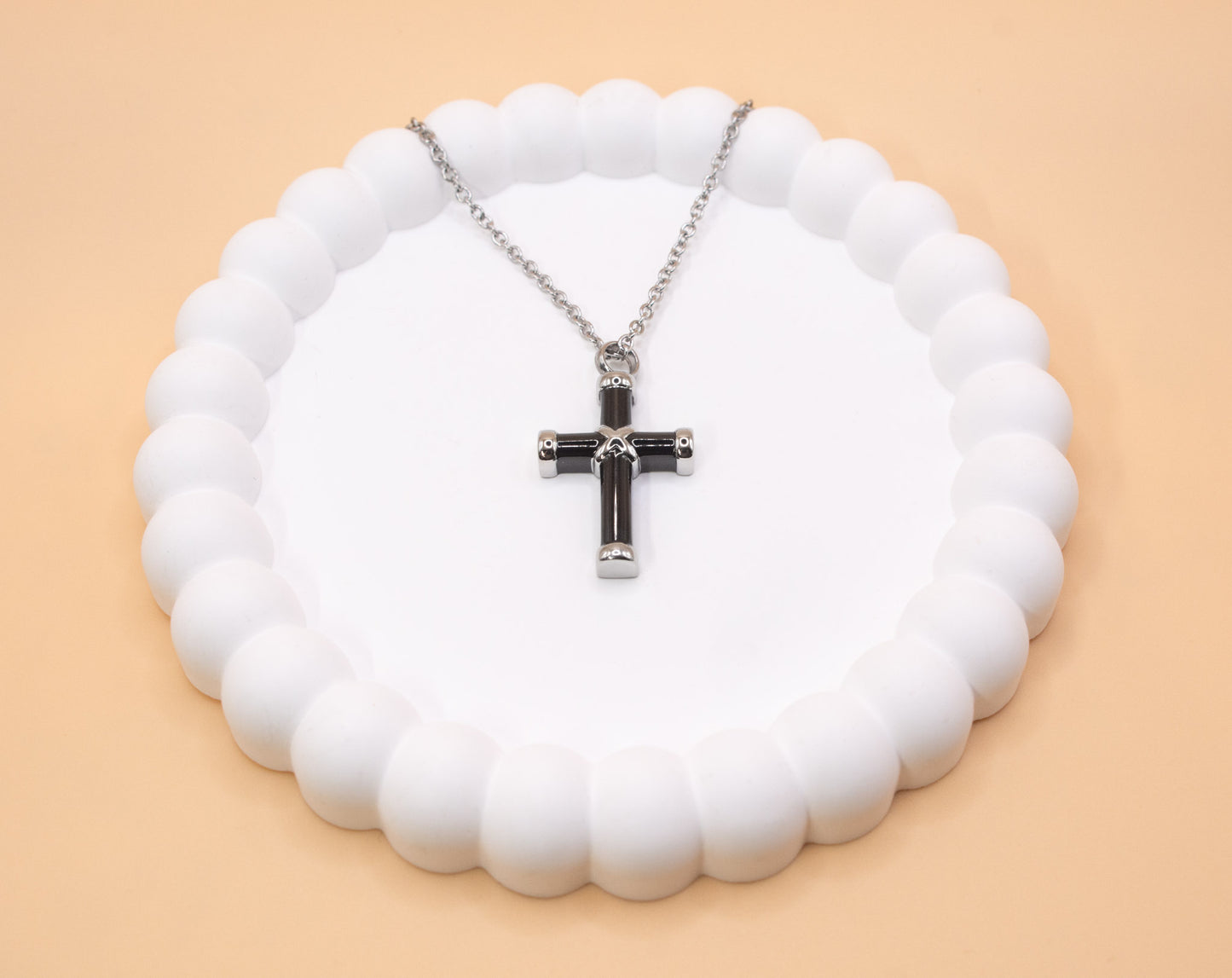 An alternative view of the black and silver stainless steel cross pendant, which can be self-filled with cremation ashes or sand from a loved ones favourite beach