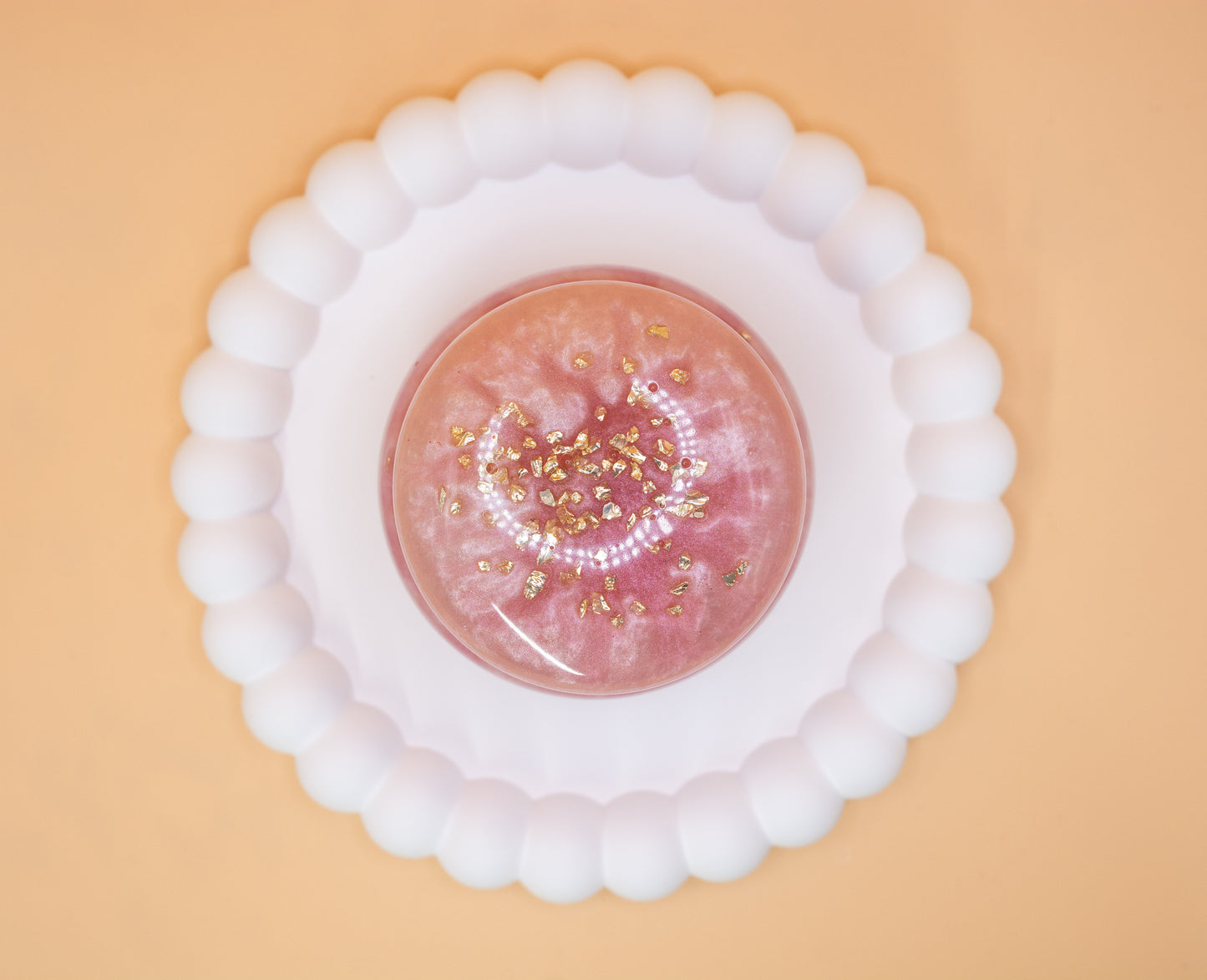 An overhead view of a metallic pearl pink handmade trinket pot, which has gold sparkle fragments in it, the lid is on the pot