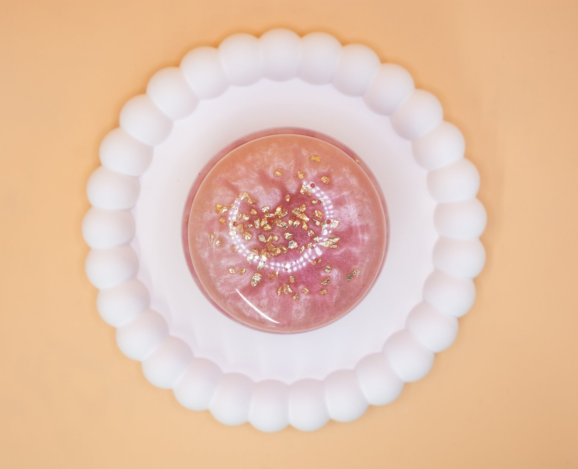 An overhead view of a metallic pearl pink handmade trinket pot, which has gold sparkle fragments in it, the lid is on the pot