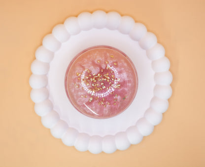 An overhead view of a metallic pearl pink handmade trinket pot, which has gold sparkle fragments in it, the lid is on the pot