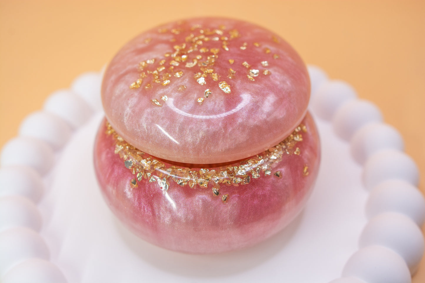 A close up view of a metallic pearly pink handcrafted trinket pot, which contains gold sparkle fragments