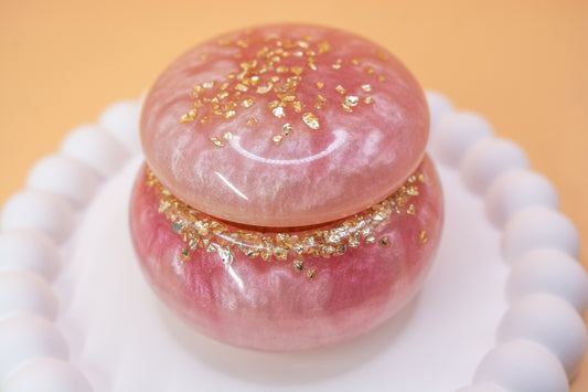 A close up view of a metallic pearly pink handcrafted trinket pot, which contains gold sparkle fragments